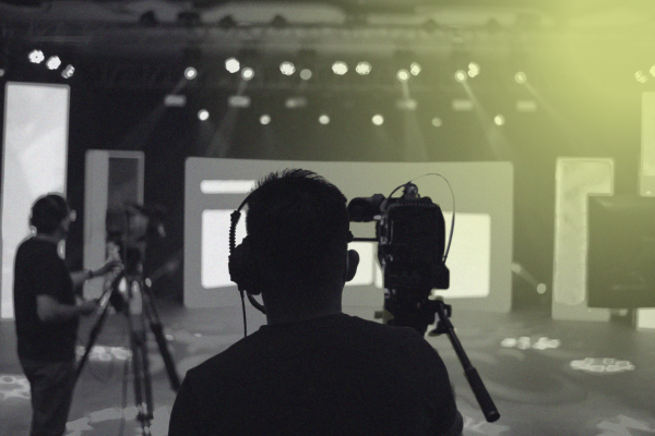 Two camera operators filming with tripod-mounted cameras on a lit studio set