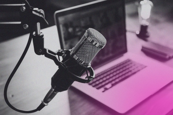 A condenser microphone on a boom arm in front of an open laptop