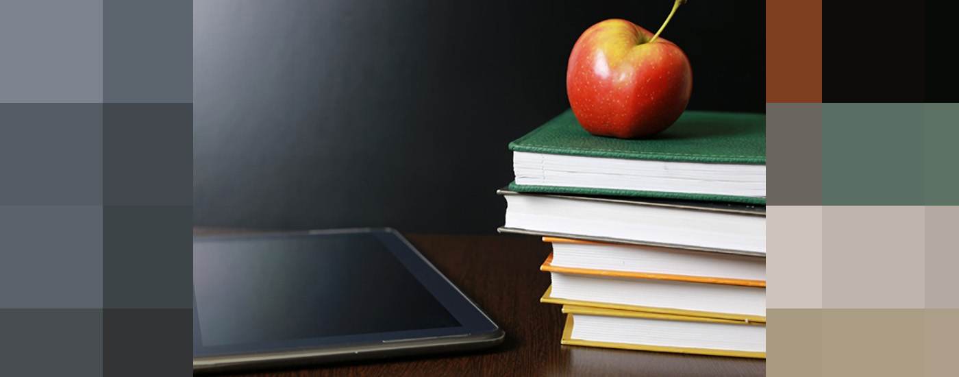 a stack of books with an apple on top, and an iPad next to the books.