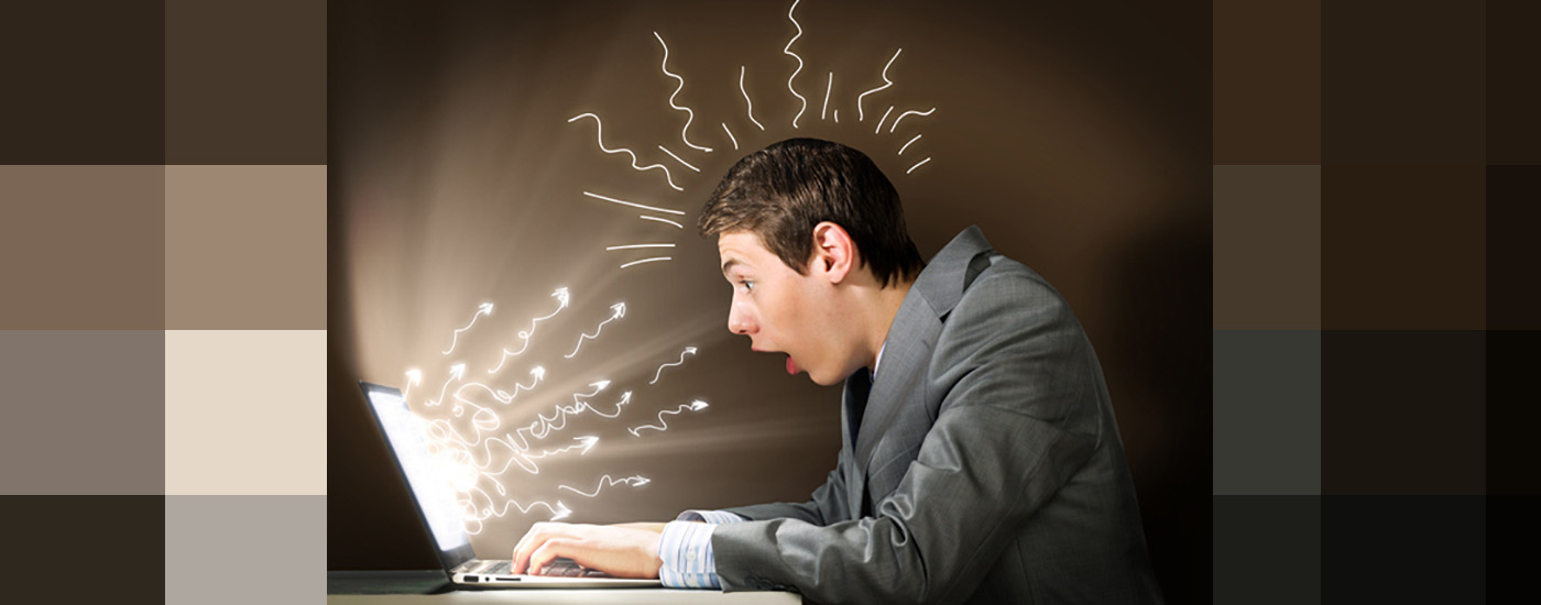 young man looking shocked at his computer screen