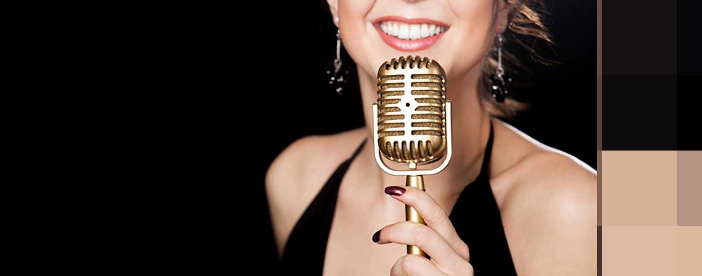 A women smiling as she holds a microphone to her face