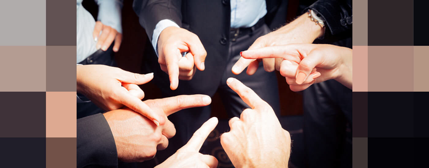 Business professionals in a circle holding out their index finger at one another