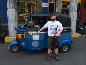 Tony poses in front of a Bajaj, a three wheeled vehicle used to transport people, in Jakarta, Indonesia 