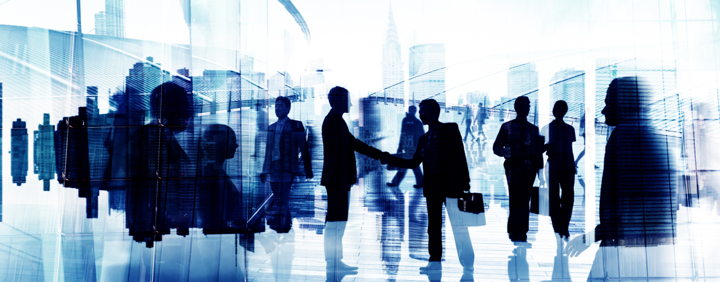 Silhouette of business professionals shaking hands and walking in front of city skyline