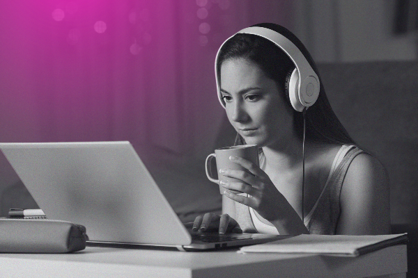 woman drinking coffee watching video on laptop with headphones