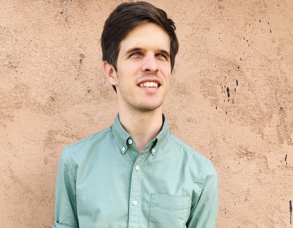 Mac Potts smiling wearing a mint green button up shirt.