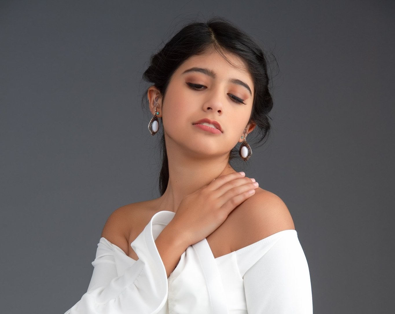 Kaylee Lartigue models and wears a white blouse with dangling earrings.