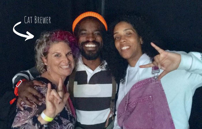 Cat Brewer and her two friends stand together with big smiles and sign “I love You” in American Sign Language.