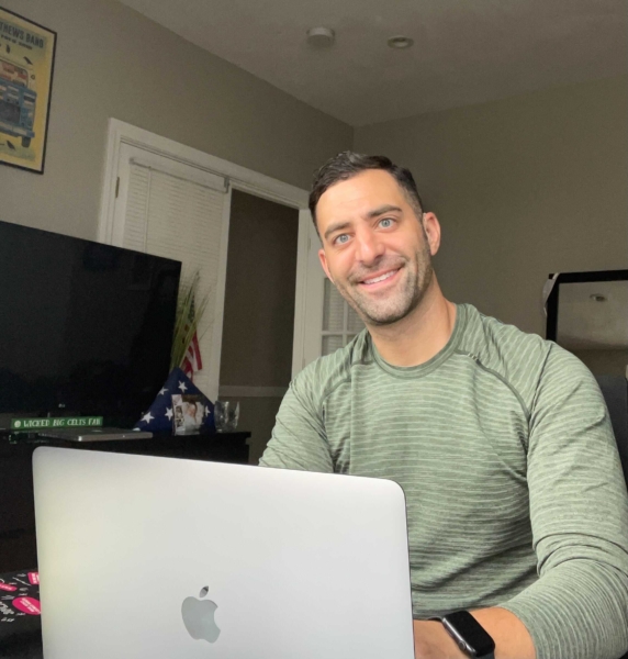 Dustin Feldman, a white man with dark hair, sits with his laptop