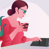 woman uses laptop while holding a coffee mug