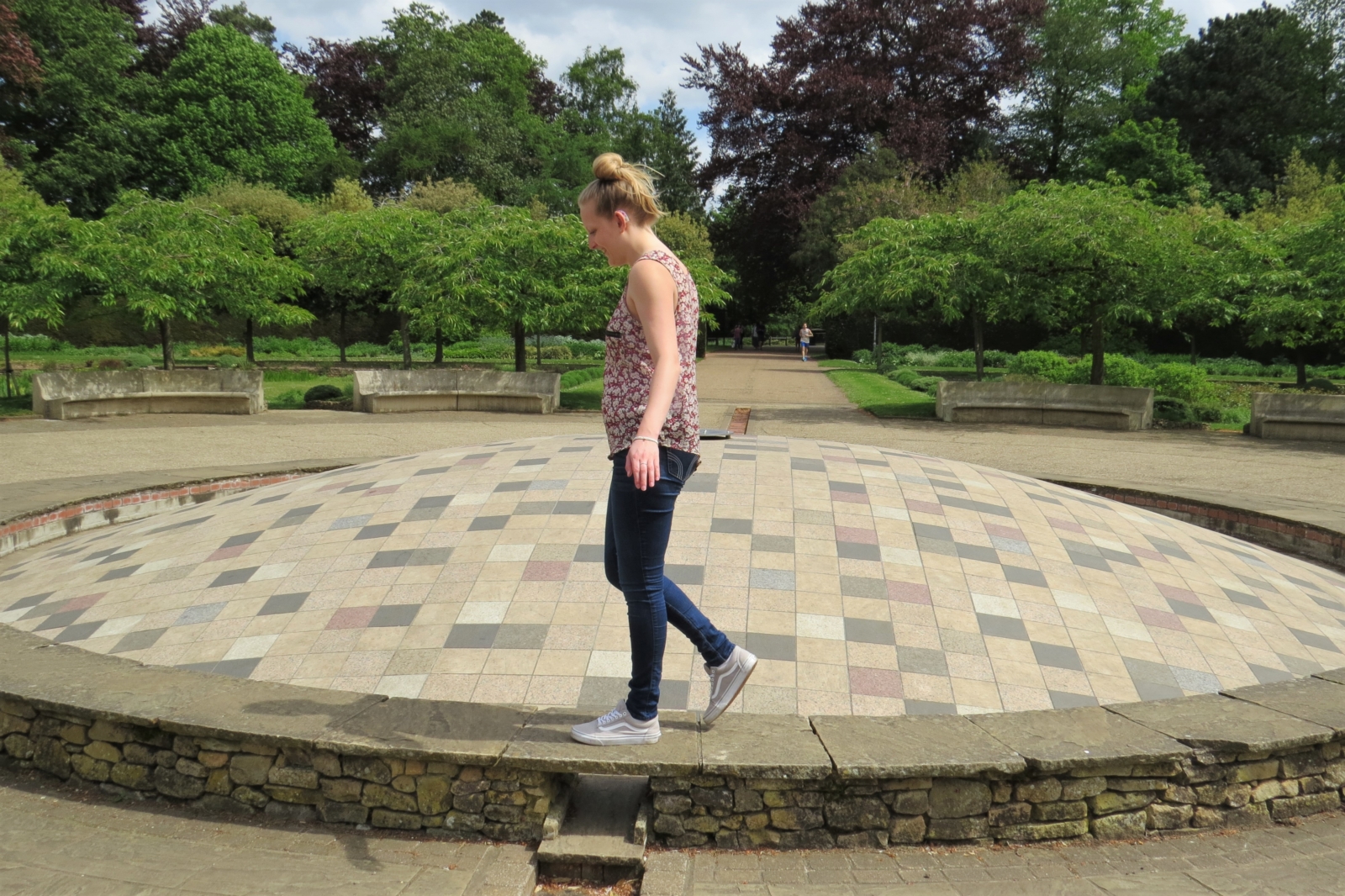 E balances on a brick ledge with trees in the background.