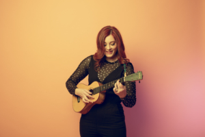 Mandy Harvey looks down as she plays the ukulele