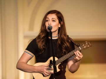 Mandy Harvey plays the ukulele while singing into a microphone