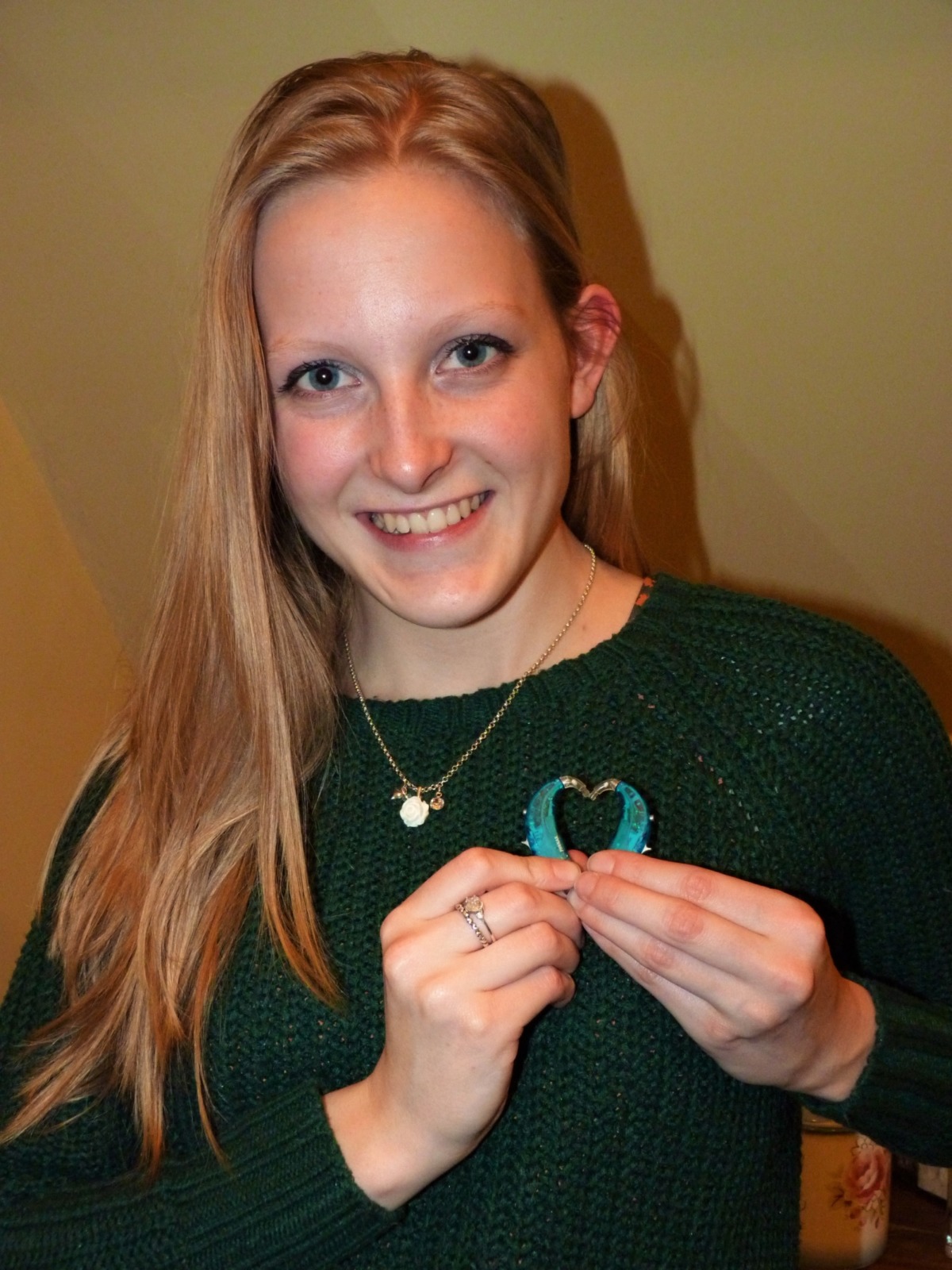 E smiles and forms a heart shape from her hearing aids.