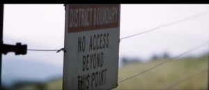 Sign on barbed wire fence reads: District boundary. No access beyond this point