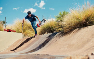 Justin Bishop is on a course with his skateboard in one hand and white cane in the other