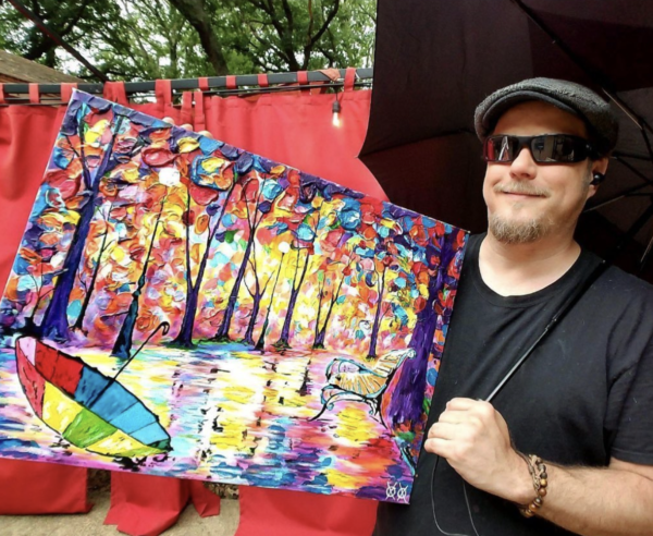 John Bramblitt holds a colorful painting of an unmbrella and a rainy day.