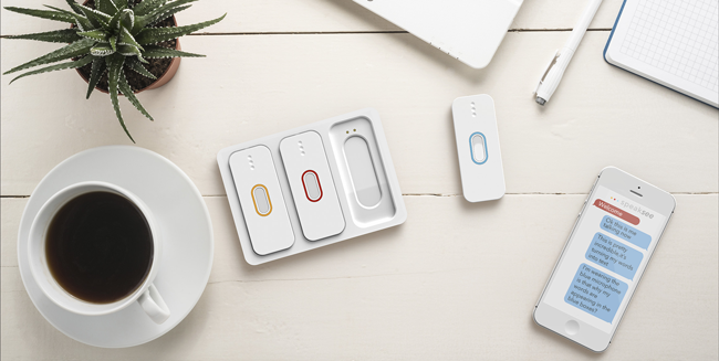 Speaksee device on a table. you see a conversation on an iphone and three colored microphones