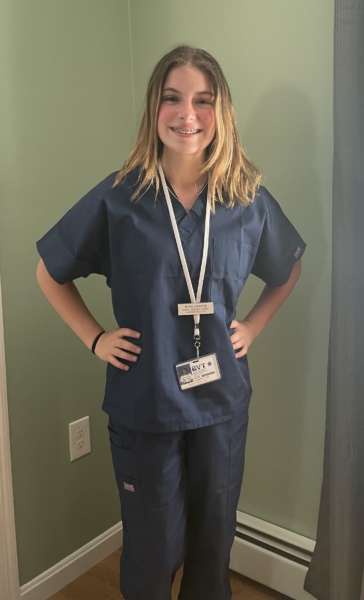 Trysta wearing blue scrubs as a dental assisting student.