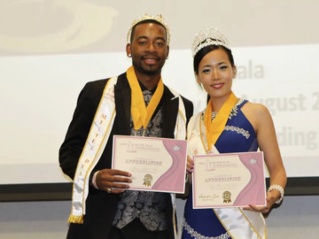 Aarro Loggins with sash and certificate for Mister Deaf International, poses with Miss Deaf International