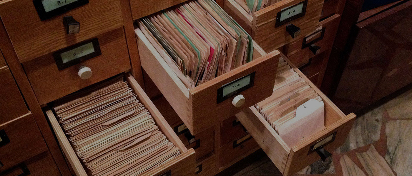 Four wooden drawers shown pulled out containing files organized alphabetically.