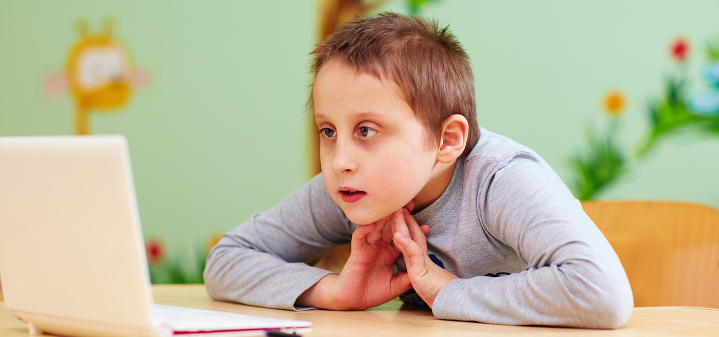 young boy with special needs watching video through the laptop