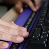 a blind person's hands using a digital braille keyboard