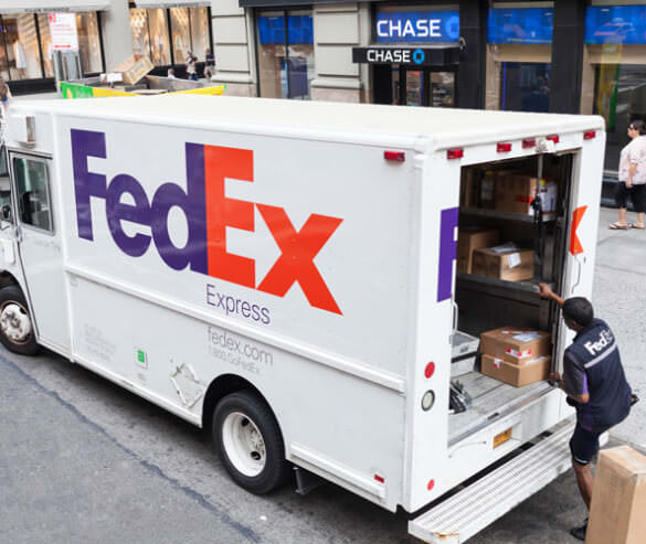 A FedEx worker loading a FedEx delivery truck