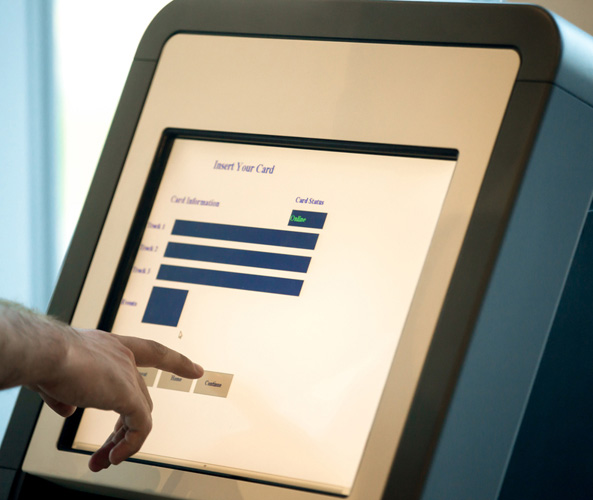 A mans hand is pressing a button on a kiosk screen