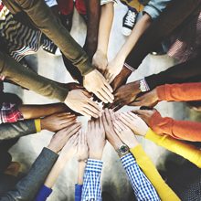 People reaching hands into the middle of a circle