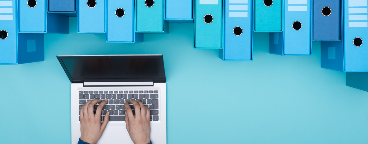 Organized archive with ring binders and woman searching for file formats in the database using a laptop, top view