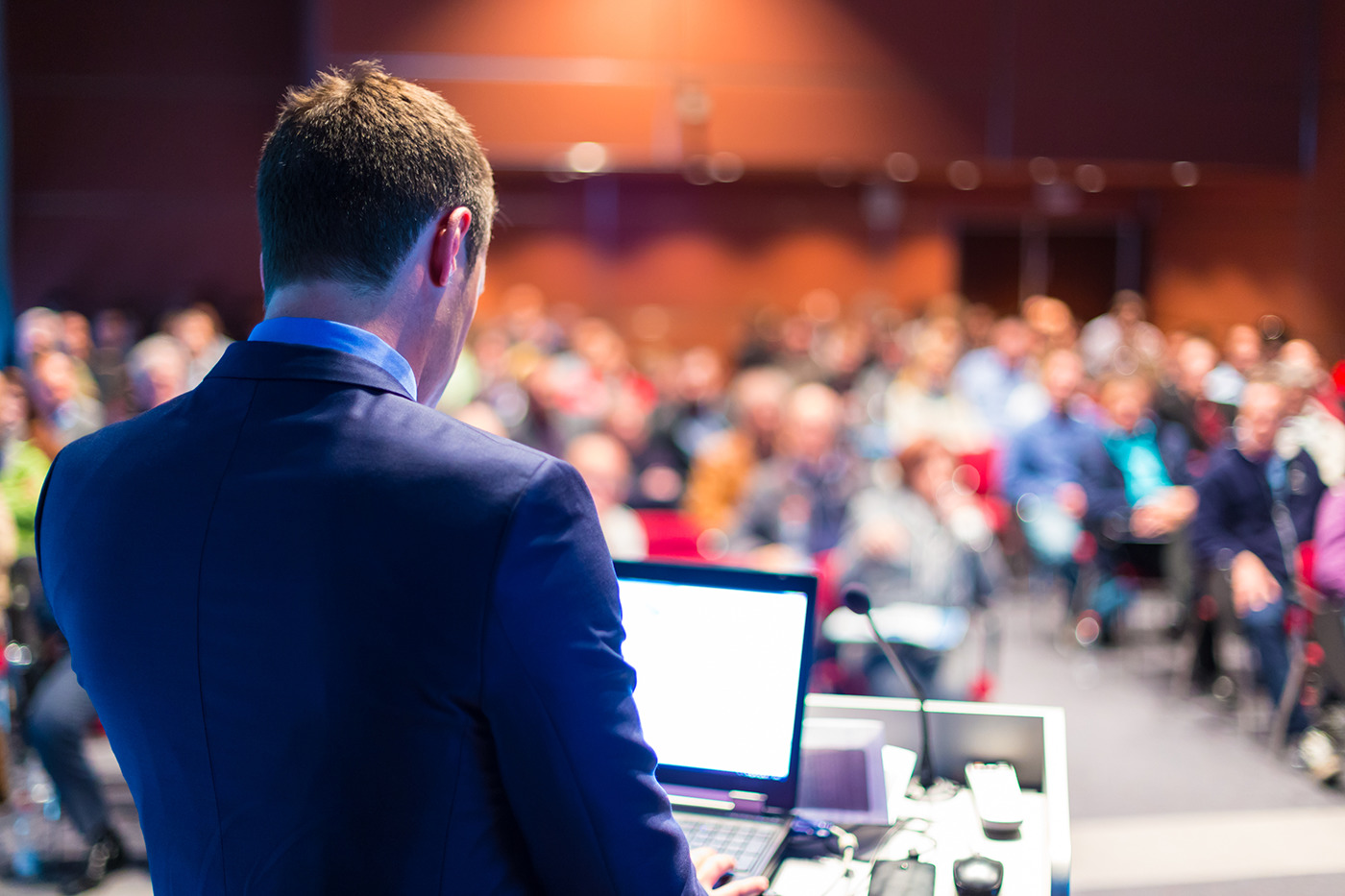 A man standing in front of a large audience at a podium.